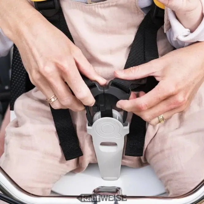 Personenhände, die den Kindersitzgurt mit schwarzen Gurten am Fahrradkindersitz bedienen